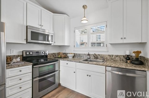 A kitchen with white cabinets and a granite countertop.