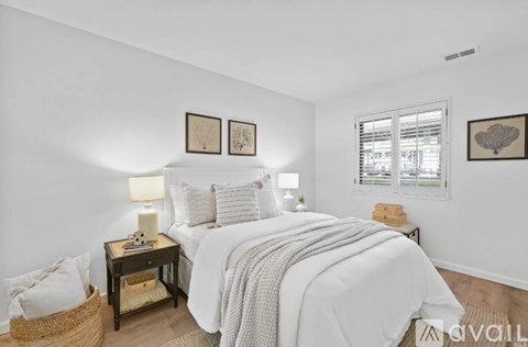 A bedroom with a large bed and two pictures on the wall.
