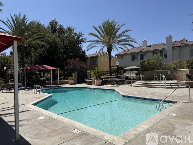 A pool surrounded by palm trees and a red awning.