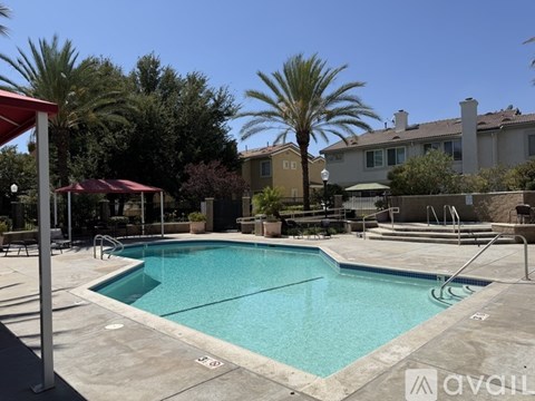 A pool surrounded by palm trees and a red awning.