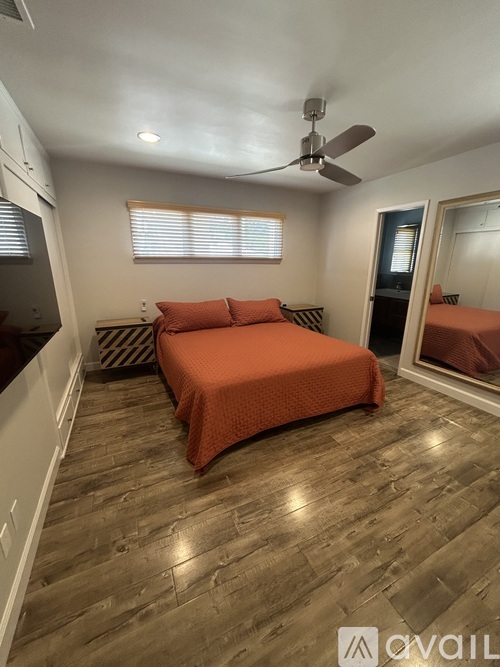 A bedroom with a bed, a ceiling fan, and a window with blinds.