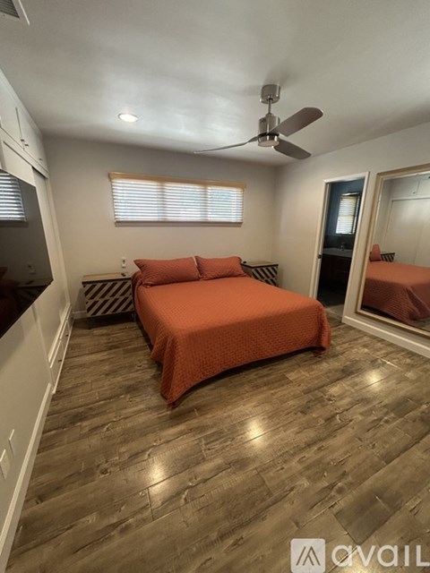 A bedroom with a bed, a ceiling fan, and a window with blinds.