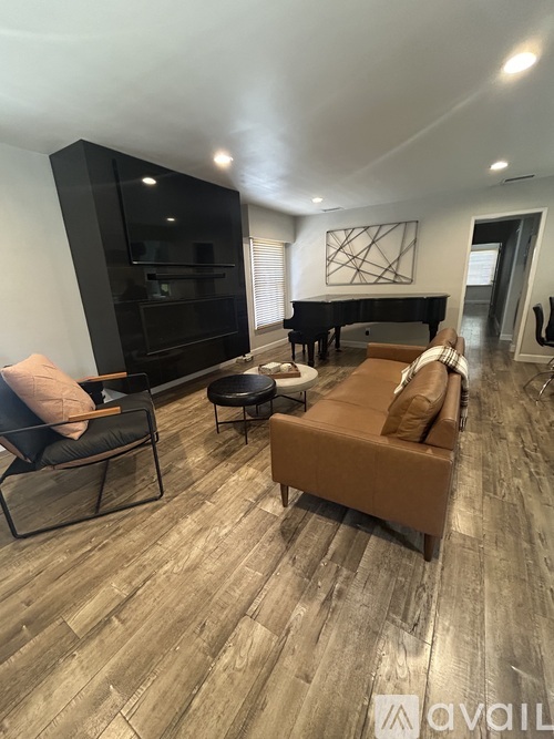 A living room with a brown couch and a black piano.