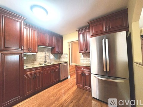 A kitchen with wooden cabinets and a stainless steel refrigerator.