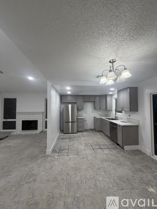 A kitchen with a refrigerator, sink, and cabinets.