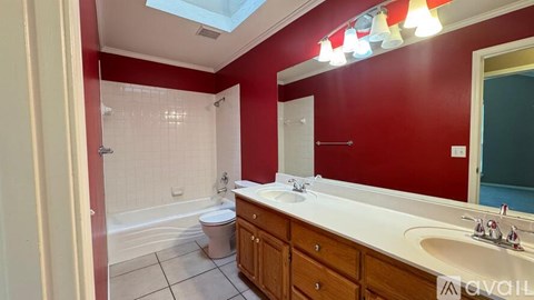 A bathroom with red walls and a skylight.