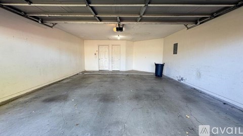 A large, empty room with a door at the end and a trash can in the middle.