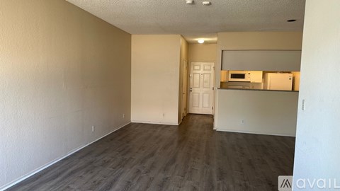 A spacious room with wooden flooring and white walls.