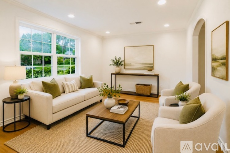 A living room with a white sofa, a coffee table, and a large window.