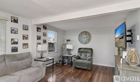 A living room with a grey couch, a black table, a green leather chair, and a television.