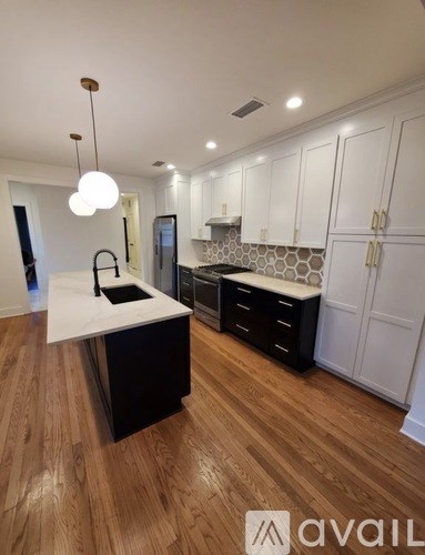 A kitchen with a white counter top and wooden floors.