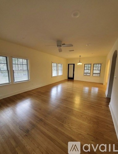 A spacious room with wooden flooring and a ceiling fan.