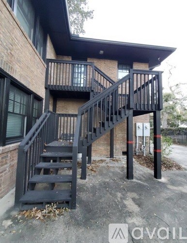 A black metal staircase with a glass balustrade leads up to a building.