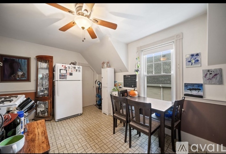 A kitchen with a refrigerator, table, and chairs.
