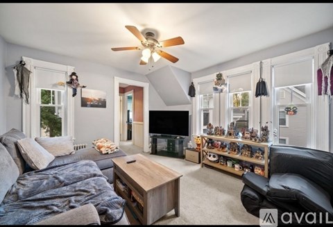 A living room with a grey couch, a wooden coffee table, and a ceiling fan.