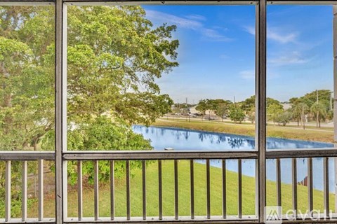 A view from a balcony looking out at a pool and trees.
