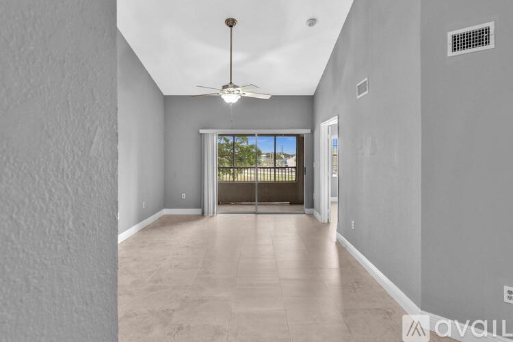 A spacious room with a ceiling fan and a door leading to a balcony.