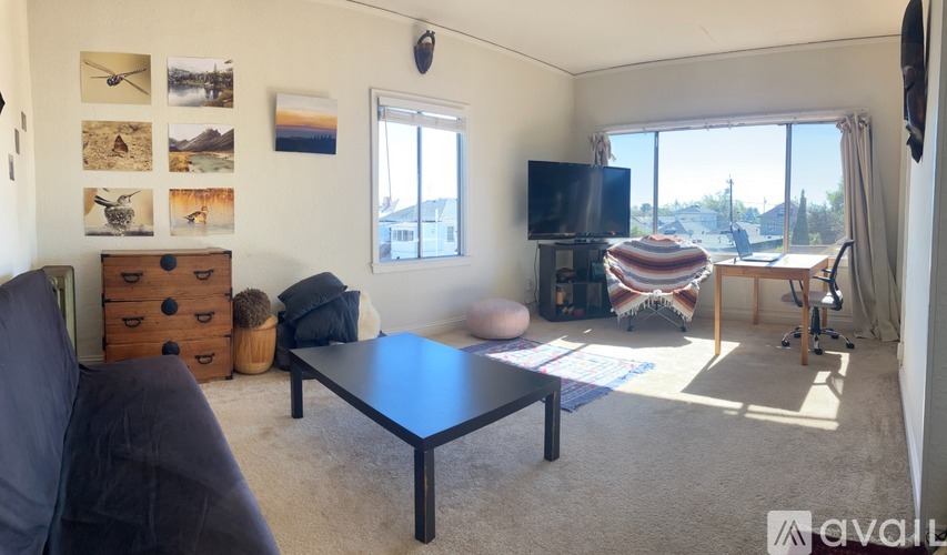 A living room with a couch, a coffee table, a television, and pictures on the wall.