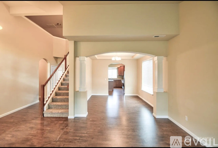 A spacious hallway with a staircase on the left and a doorway on the right.