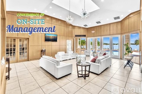 A spacious living room with a sign that reads "CONVENIENCE OF ON-SITE MANAGEMENT" and a view of the outdoors through the windows.