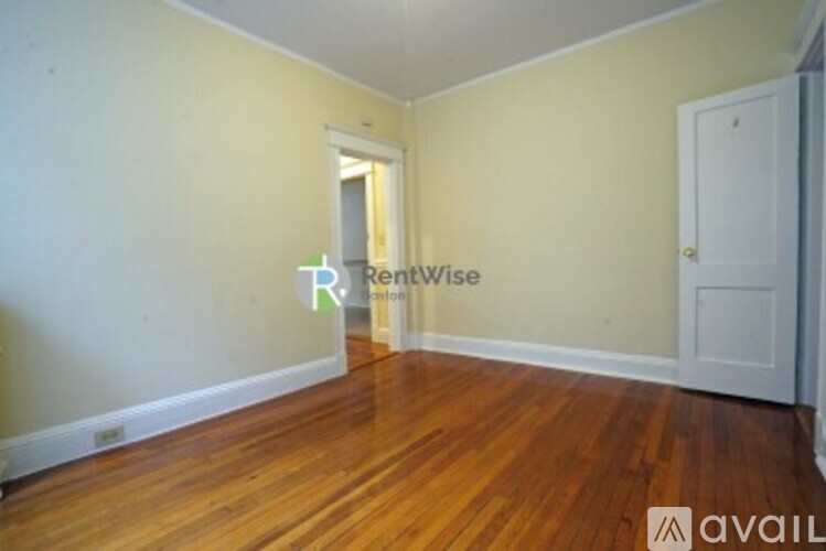 A room with wooden floors and a doorway leading to another room.