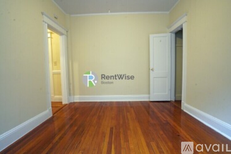 A room with a wooden floor and a RentWise Boston logo on the wall.
