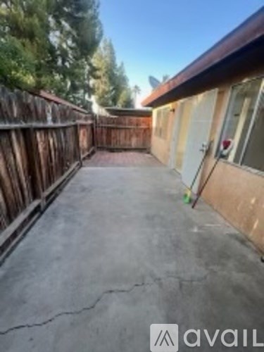A backyard with a wooden fence and a concrete patio.