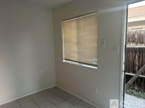 A room with a window covered by blinds and a white wall.
