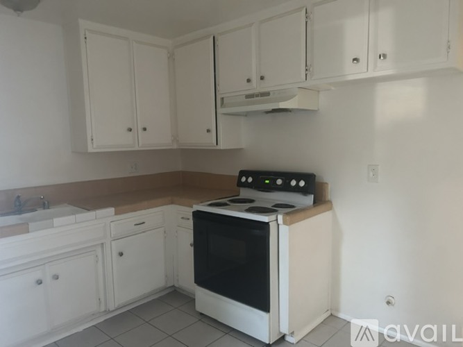 A kitchen with white cabinets and a black stove top oven.