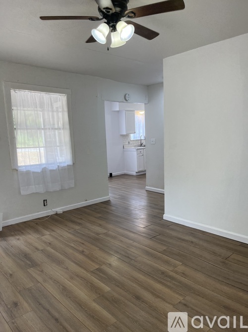A room with a ceiling fan and wooden flooring.