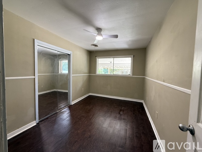 A room with a sliding glass door and wood flooring.