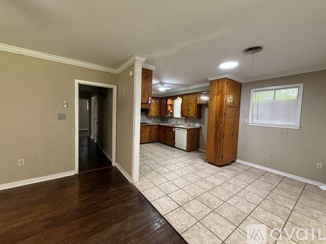 A kitchen area with a sink, cabinets, and a window.