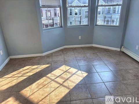 A room with tile flooring and two windows letting in sunlight.