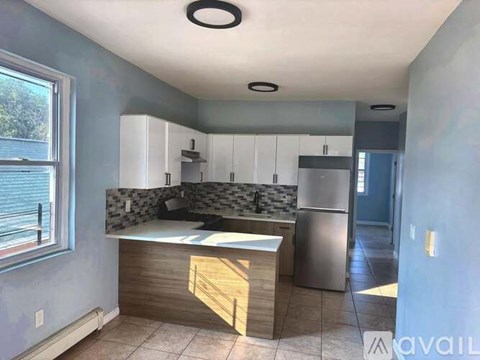 A kitchen with a stainless steel refrigerator and a countertop with a sink.
