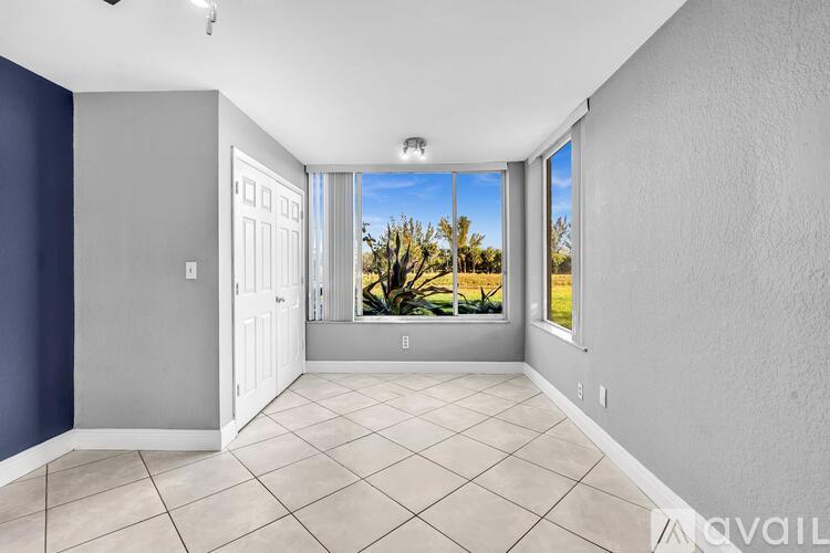A spacious room with a view of a tree-lined street through the window.