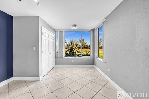 A spacious room with a view of a tree-lined street through the window.