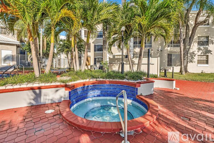 A small pool surrounded by a brick patio and palm trees.