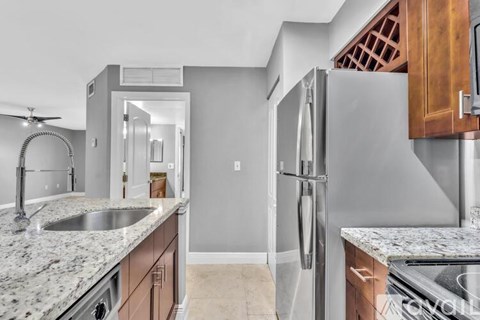 A kitchen with a sink, refrigerator, and a stove top oven.