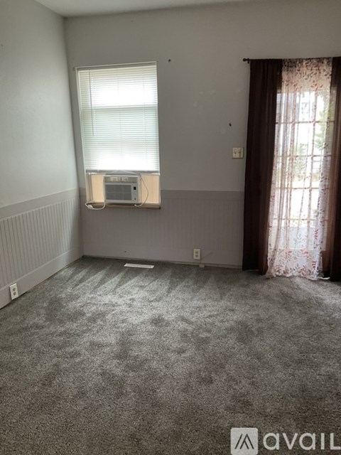 A room with a carpeted floor and a window with blinds.