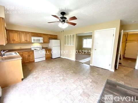 A kitchen with a refrigerator, sink, and cabinets.