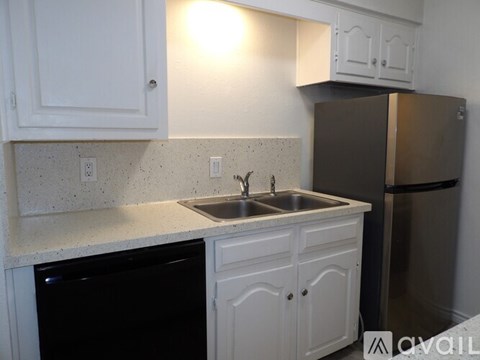A kitchen with white cabinets and a black dishwasher.