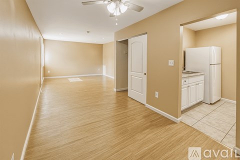 A spacious room with wooden flooring and a ceiling fan.