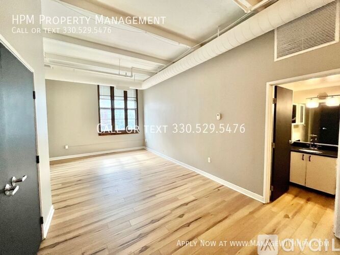 A spacious room with wooden flooring and a large window is on the market with HPM Property Management.
