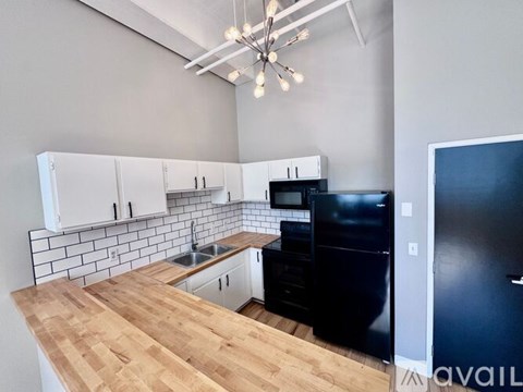A kitchen with black appliances and wooden countertops.