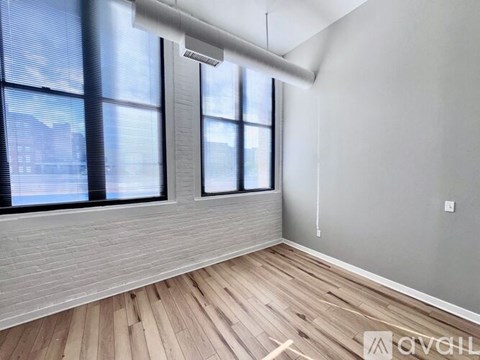 A room with wooden flooring and large windows.