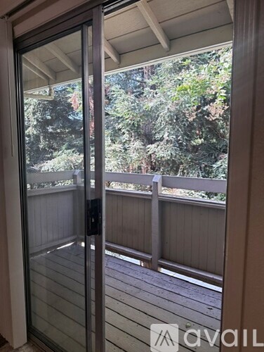 A glass door with a wooden deck and trees in the background.