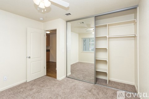 A bedroom with a mirrored closet door and a carpeted floor.