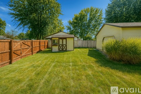 A backyard with a fence, a shed, and a grassy area.
