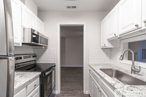 A kitchen with white cabinets and a stainless steel oven.
