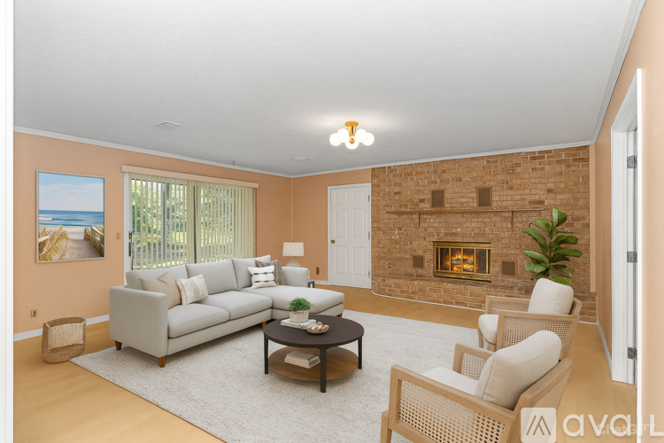 A living room with a grey couch, a coffee table, a fireplace, and a painting of a beach scene on the wall.